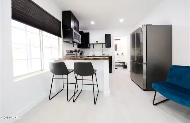 kitchen with kitchen peninsula, a kitchen breakfast bar, white electric range, and stainless steel refrigerator