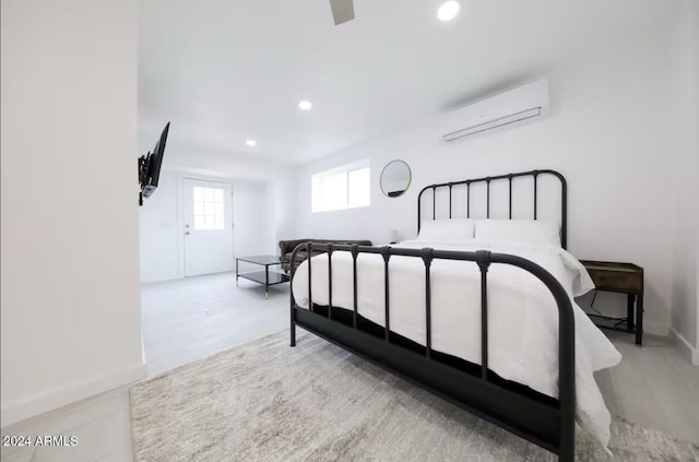 bedroom featuring a wall unit AC and light hardwood / wood-style flooring