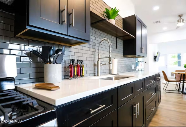 kitchen with decorative backsplash, light wood-type flooring, ceiling fan, and sink