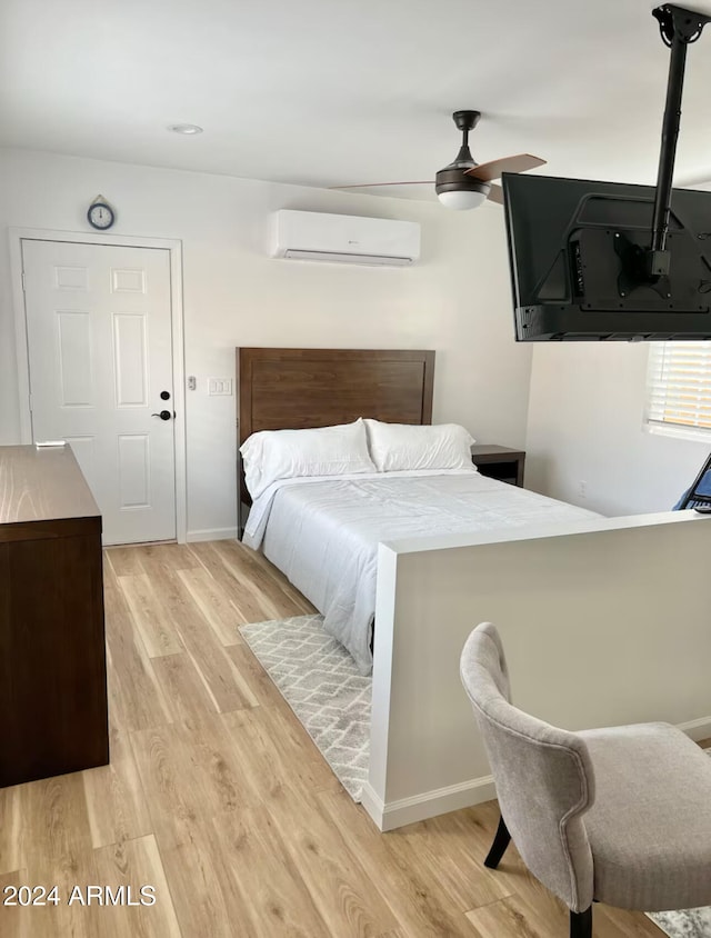 bedroom with light hardwood / wood-style flooring, a wall mounted AC, and ceiling fan