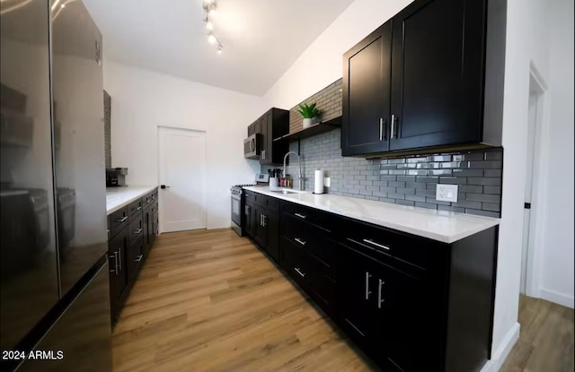 kitchen with sink, stainless steel appliances, tasteful backsplash, and light hardwood / wood-style flooring