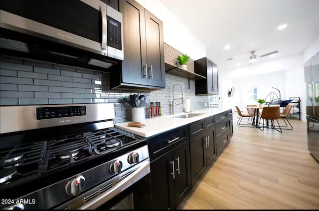 kitchen with sink, decorative backsplash, ceiling fan, light hardwood / wood-style floors, and stainless steel appliances