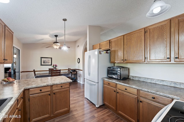 kitchen featuring wood-type flooring, white refrigerator, hanging light fixtures, ceiling fan, and a textured ceiling