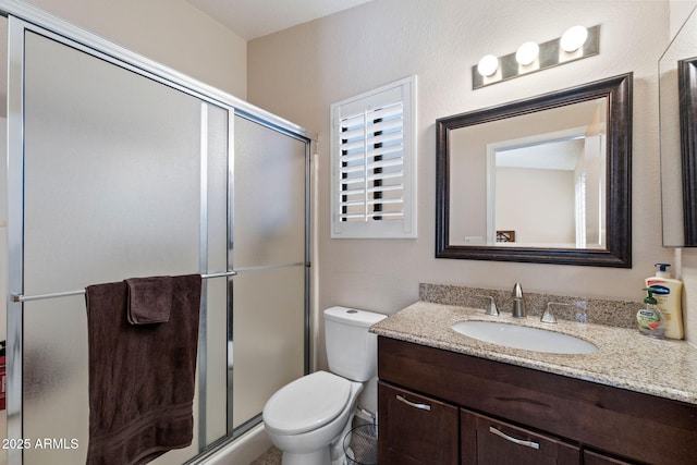 bathroom featuring vanity, toilet, and a shower with door