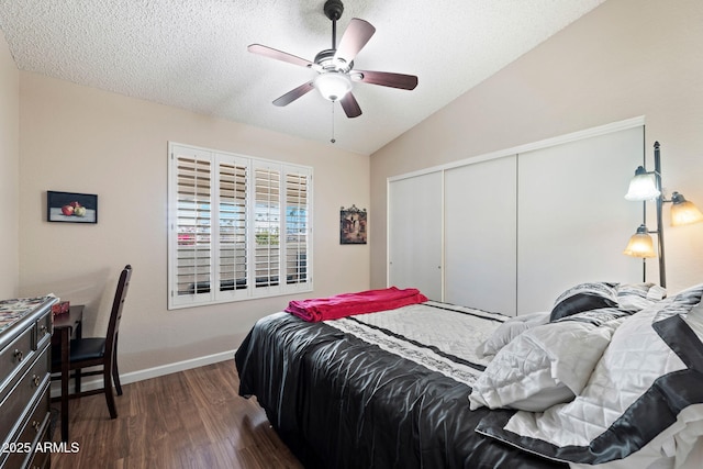 bedroom with lofted ceiling, a textured ceiling, dark hardwood / wood-style flooring, a closet, and ceiling fan