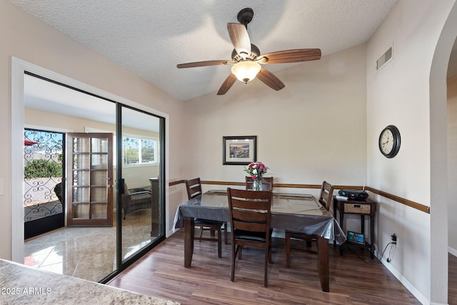 dining room with lofted ceiling, ceiling fan, light hardwood / wood-style floors, and a textured ceiling