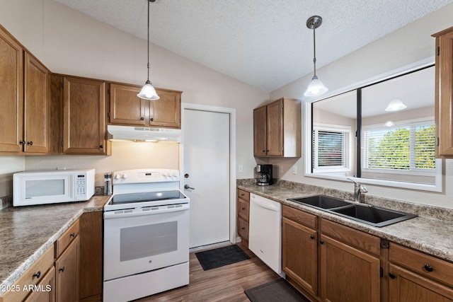 kitchen featuring lofted ceiling, sink, dark hardwood / wood-style flooring, pendant lighting, and white appliances