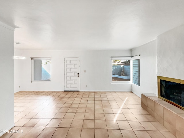 unfurnished living room with a tiled fireplace and light tile patterned floors