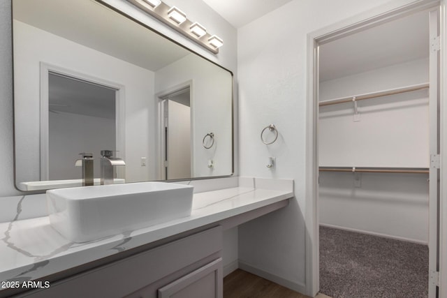 bathroom featuring a spacious closet, vanity, and baseboards