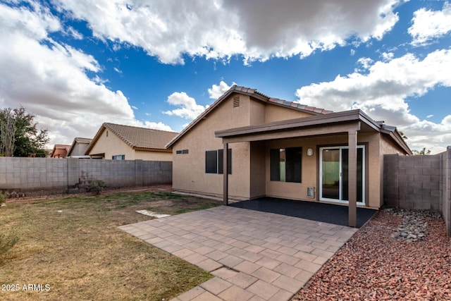 back of house with a yard, a fenced backyard, a patio, and stucco siding