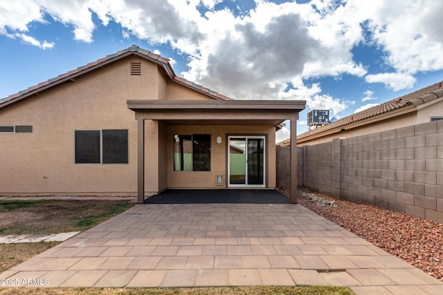 rear view of house featuring a fenced backyard, a tile roof, a patio, and stucco siding