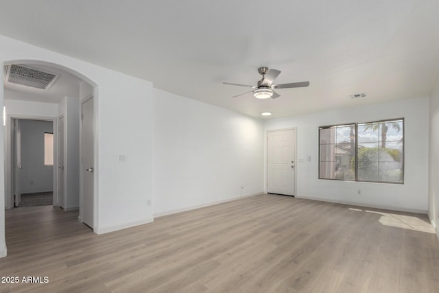 unfurnished room featuring arched walkways, baseboards, visible vents, and light wood finished floors