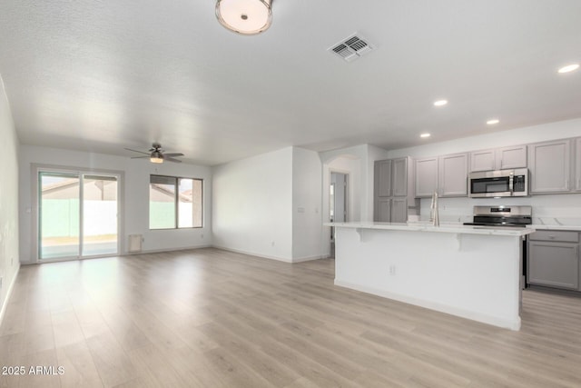 kitchen featuring visible vents, appliances with stainless steel finishes, gray cabinets, light countertops, and light wood-type flooring