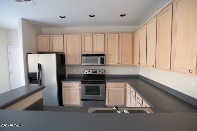 kitchen with a sink, stainless steel appliances, dark countertops, and light brown cabinets