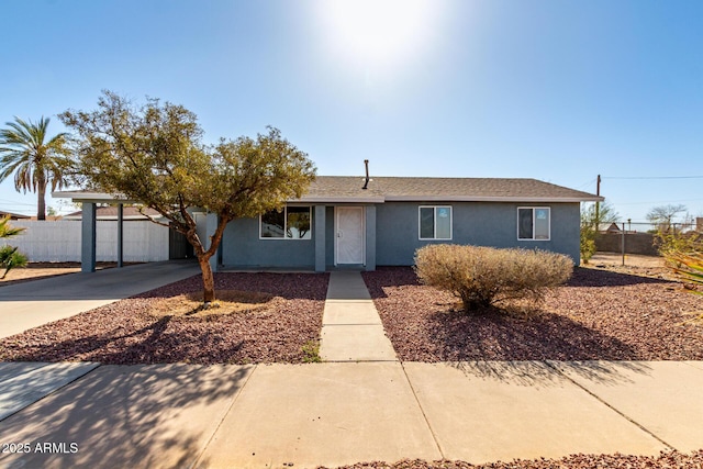 ranch-style home featuring a carport, fence, driveway, and stucco siding