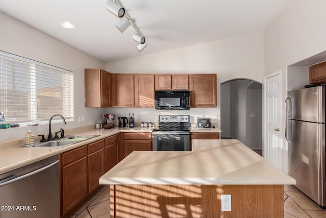 kitchen featuring sink, a center island, lofted ceiling, light tile patterned floors, and appliances with stainless steel finishes