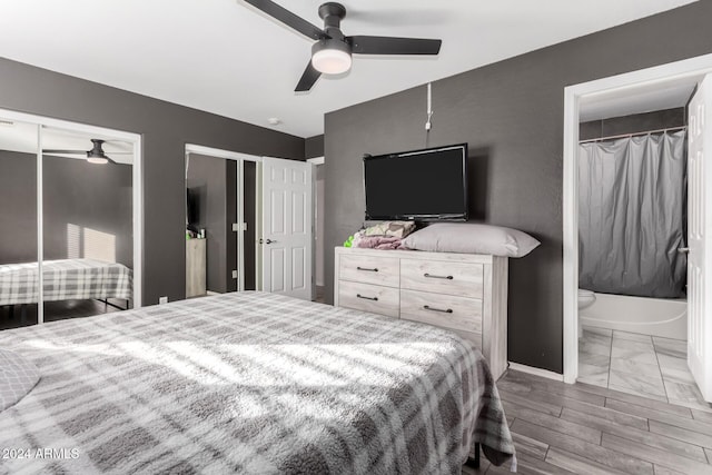 bedroom featuring hardwood / wood-style flooring, ceiling fan, ensuite bath, and two closets