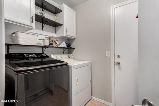 laundry area featuring cabinets, light tile patterned floors, and washing machine and clothes dryer