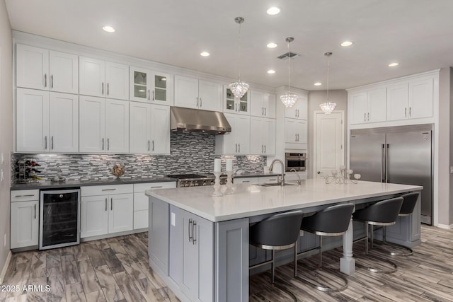 4519 N 29th Way, Phoenix, AZ 85016 - kitchen featuring beverage cooler, under cabinet range hood, appliances with stainless steel finishes, a sink, and a kitchen bar