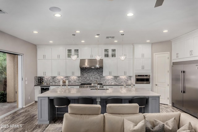 4519 N 29th Way, Phoenix, AZ 85016 - kitchen featuring stainless steel appliances, under cabinet range hood, a sink, decorative backsplash, and a kitchen island with sink