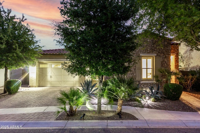 4519 N 29th Way, Phoenix, AZ 85016 - view of property hidden behind natural elements with stone siding, a garage, decorative driveway, stucco siding, and a tiled roof