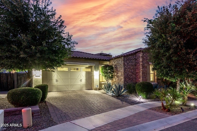 4519 N 29th Way, Phoenix, AZ 85016 - view of front of property featuring decorative driveway, a garage, a tile roof, stone siding, and stucco siding