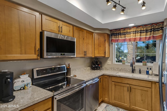 kitchen featuring appliances with stainless steel finishes, sink, light stone counters, and a tray ceiling