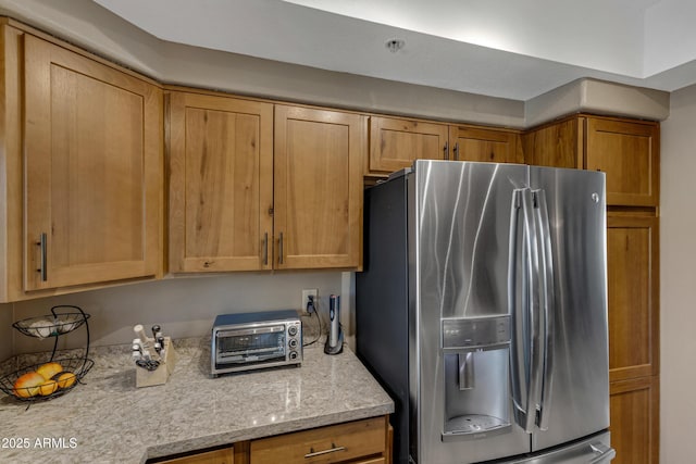 kitchen featuring light stone counters and stainless steel fridge