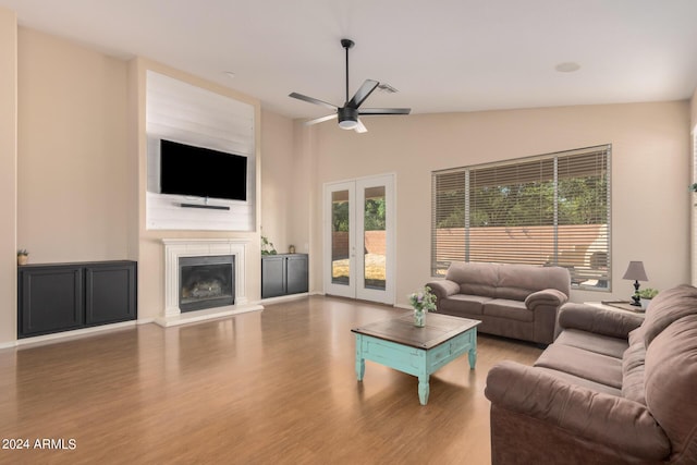 living room with french doors, lofted ceiling, a ceiling fan, a glass covered fireplace, and wood finished floors