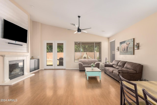 living room featuring a fireplace, visible vents, vaulted ceiling, wood finished floors, and baseboards