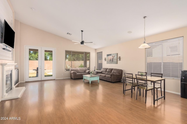 living room featuring lofted ceiling, ceiling fan, wood finished floors, visible vents, and a glass covered fireplace