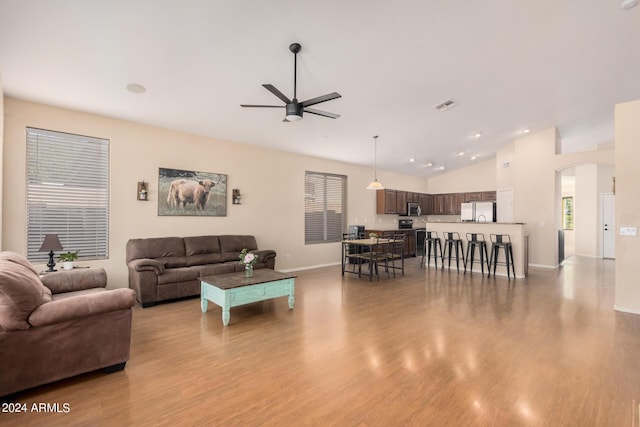 living room featuring a ceiling fan, visible vents, vaulted ceiling, and wood finished floors