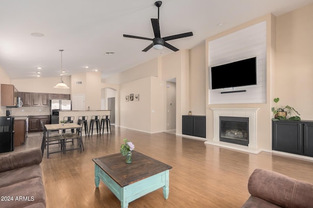 living room with lofted ceiling, a glass covered fireplace, visible vents, and wood finished floors