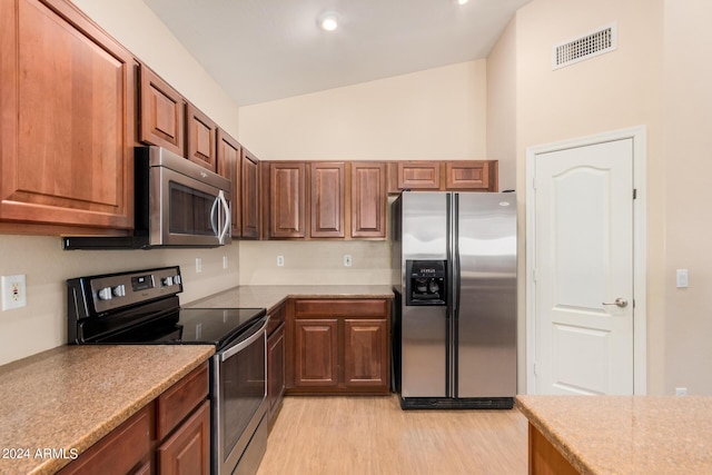 kitchen with stainless steel appliances, lofted ceiling, visible vents, and light wood finished floors