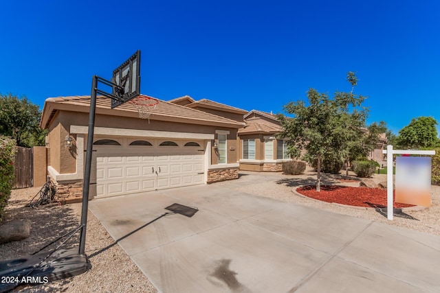 view of front of property with a tile roof, stucco siding, concrete driveway, a garage, and stone siding