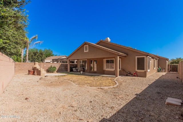 rear view of property featuring a fenced backyard, a patio, and stucco siding