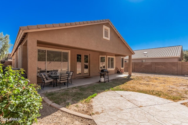 rear view of property featuring a patio area, fence, and stucco siding