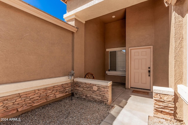 doorway to property featuring stone siding and stucco siding