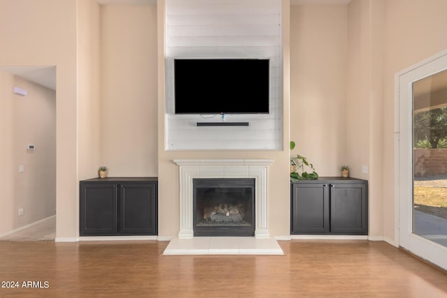 unfurnished living room with baseboards, wood finished floors, and a tile fireplace