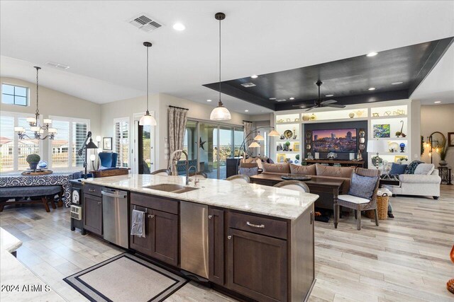 kitchen featuring light stone counters, ceiling fan with notable chandelier, hanging light fixtures, and sink