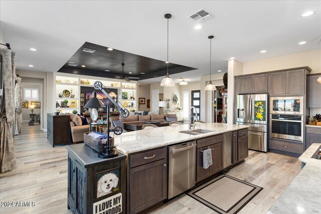 kitchen featuring sink, ceiling fan, stainless steel appliances, and light stone counters