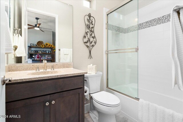 full bathroom featuring shower / bath combination with glass door, toilet, vanity, and ceiling fan