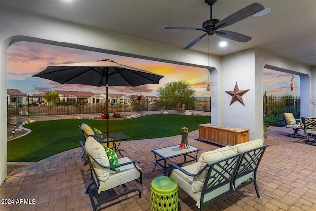 patio terrace at dusk with a yard and ceiling fan