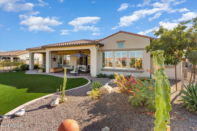 back of house featuring ceiling fan, an outdoor living space, a lawn, and a patio area