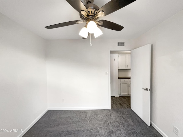 empty room with dark colored carpet and ceiling fan