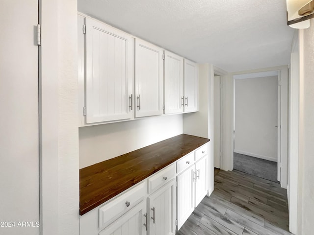 interior space featuring white cabinetry, a textured ceiling, and light wood-type flooring