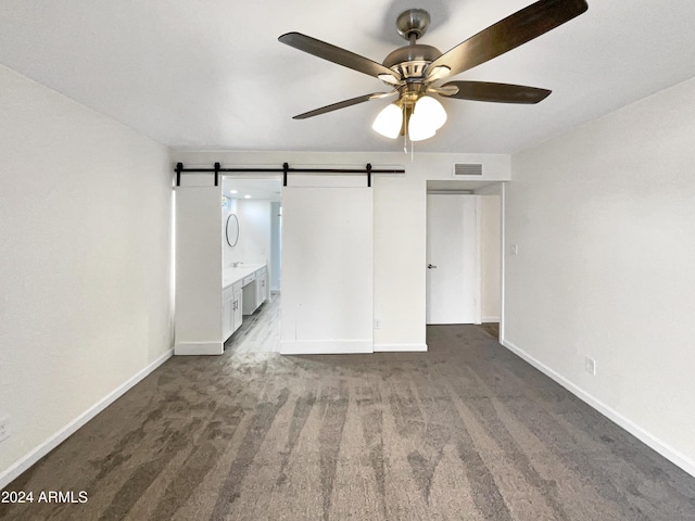 interior space with a barn door and ceiling fan