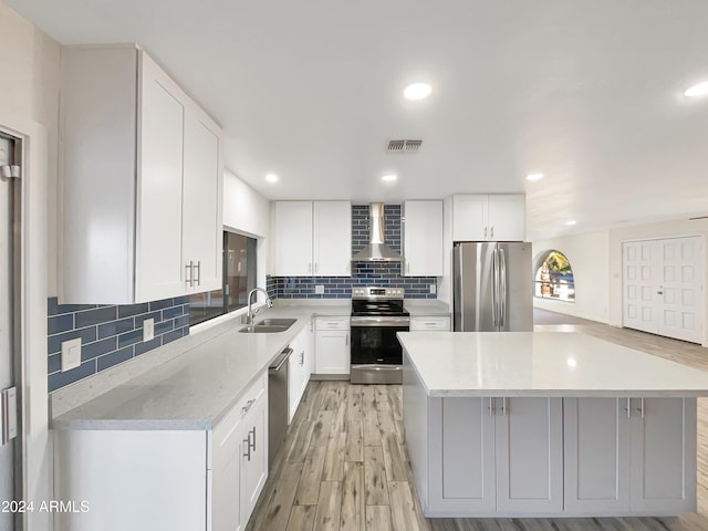 kitchen featuring white cabinets, appliances with stainless steel finishes, sink, and wall chimney range hood