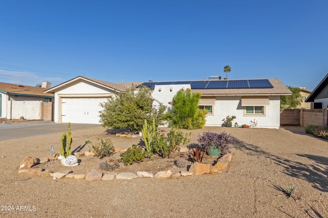 ranch-style home featuring solar panels and a garage