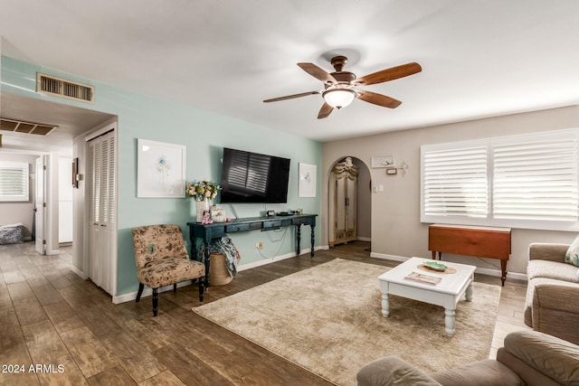 living room featuring dark wood-type flooring and ceiling fan